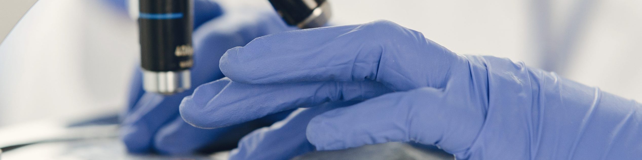 Professional bacteriologist putting blood sample on microscope, expertise.Covid-19, vaccine creation concept.